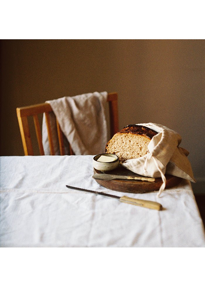 Kvadratisk poster med bröd och smör på vackert uppdukat bord.