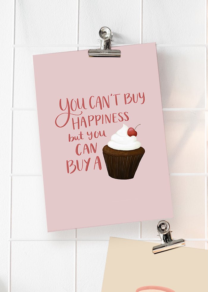 Rosa poster med humoristisk text. You can't buy happiness but you can buy a cupcake.
