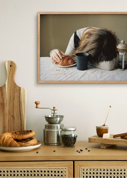 Rolig kaffeposter, foto av en tjej som somnat vid bordet med handen över en croissant och en tom kaffekopp.
